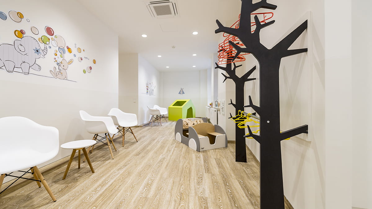 Kinderarztpraxis Hussack Leipzig Wartezimmer mit kinderfreundlichen Wandbildern, einer Garderobe in Form von Bäumen und einem Spielzeug-Auto