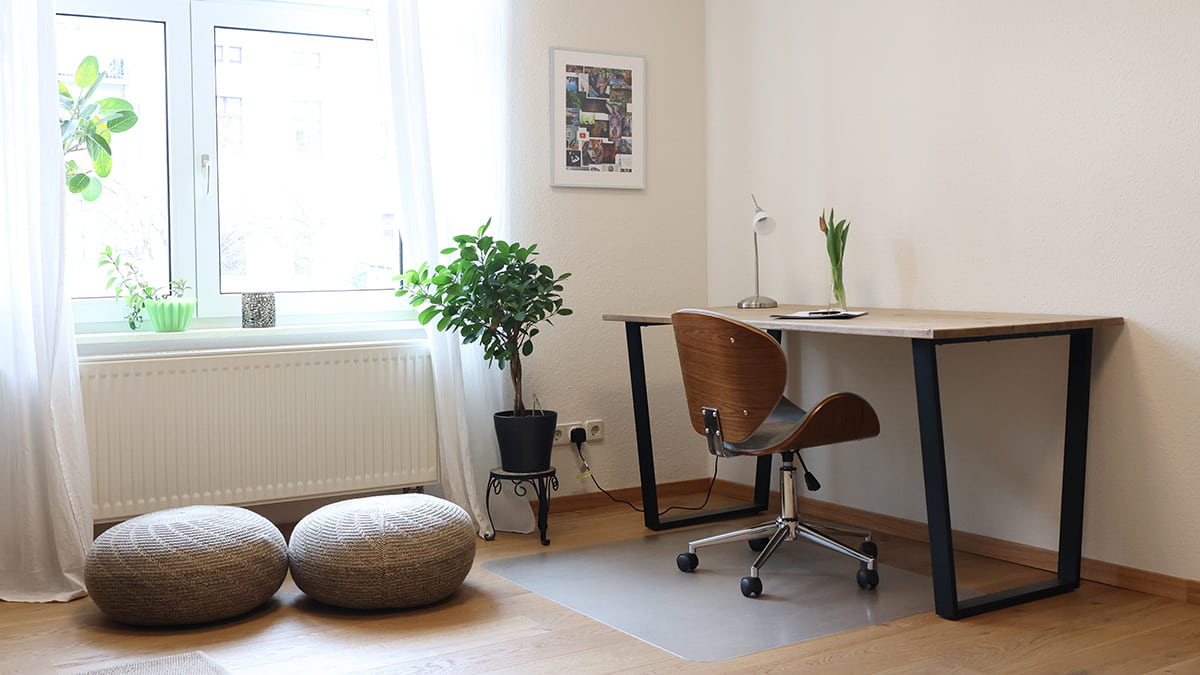 Referenz Praxis für Psychotherapie Peterhänsel Leipzig Schreibtisch mit einer kleinen Lampe, einer Vase mit Tulpen und einem hellen Fenster daneben