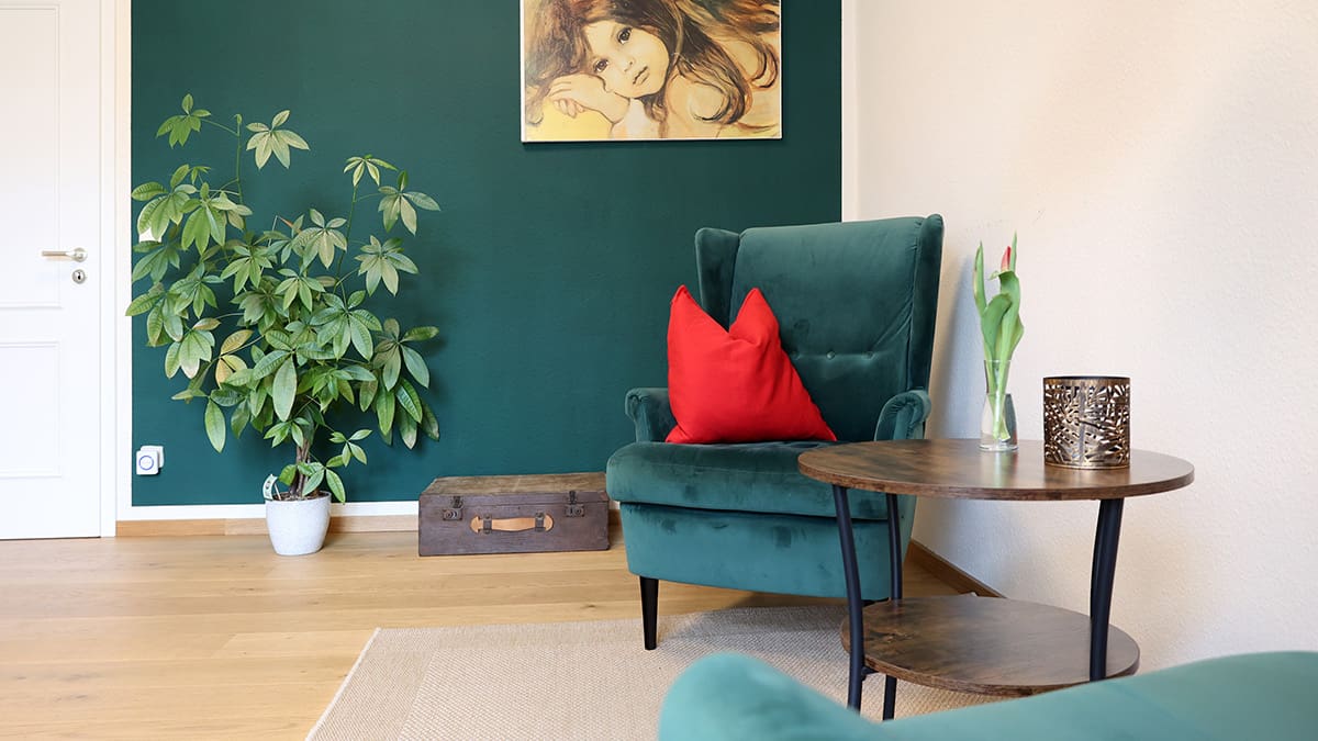 Referenz Praxis für Psychotherapie Peterhänsel Leipzig Blick von einem Sessel auf den anderen Sessel im Sprechzimmer mit einer grünen Pflanze, einer grünen Wand im Farbton der Sessel sowie einem Bild im Hintergrund